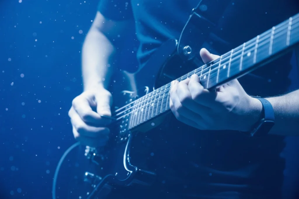 Musicien en studio enregistrant une guitare pour la création d’une identité sonore sur mesure, illustrant le prix et la production d’un projet d’audio branding.