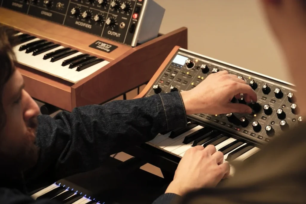 Sound designer adjusting synthesizer to create custom audio for sports event sonic identity